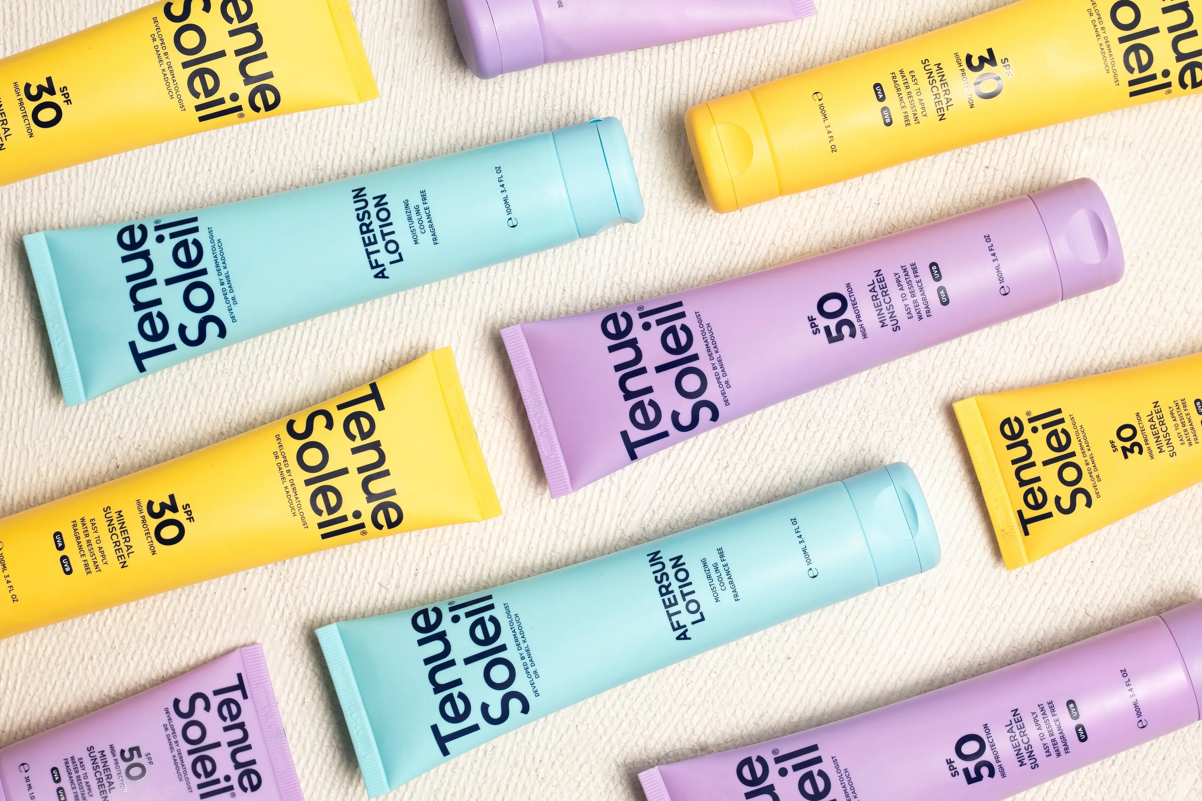 Colorful tubes of Tenue Soleil sunscreen and aftersun lotion arranged on a light surface, featuring SPF 30 and SPF 50 options.